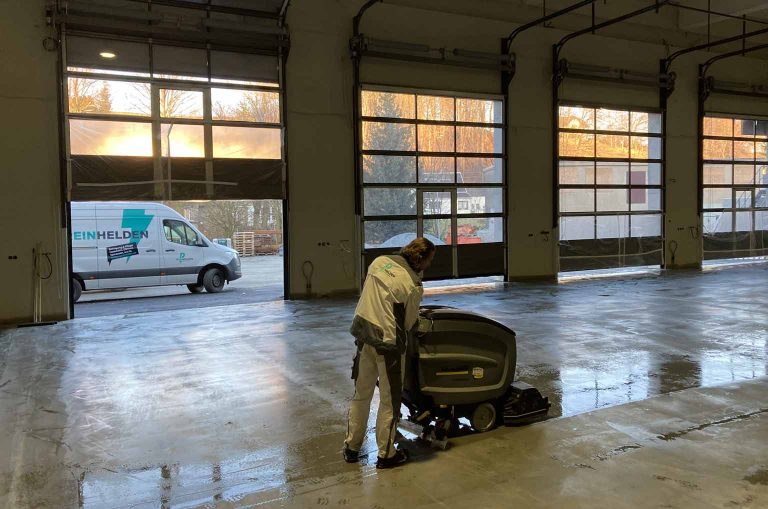 Das Bild zeigt jemanden der einen Betonboden einer Halle mit einer Maschine hydroprobiert
